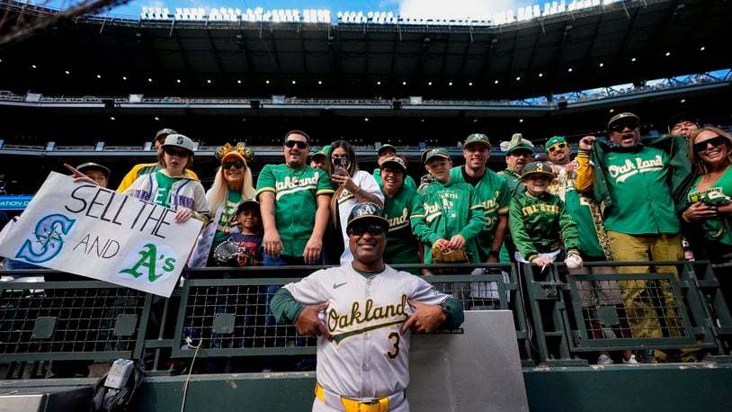 Oakland Athletics third base coach Eric Martins (3) poses with fans before a baseball game against the Seattle Mariners, Sunday, Sept. 29, 2024, in Seattle. (AP Photo/Lindsey Wasson)