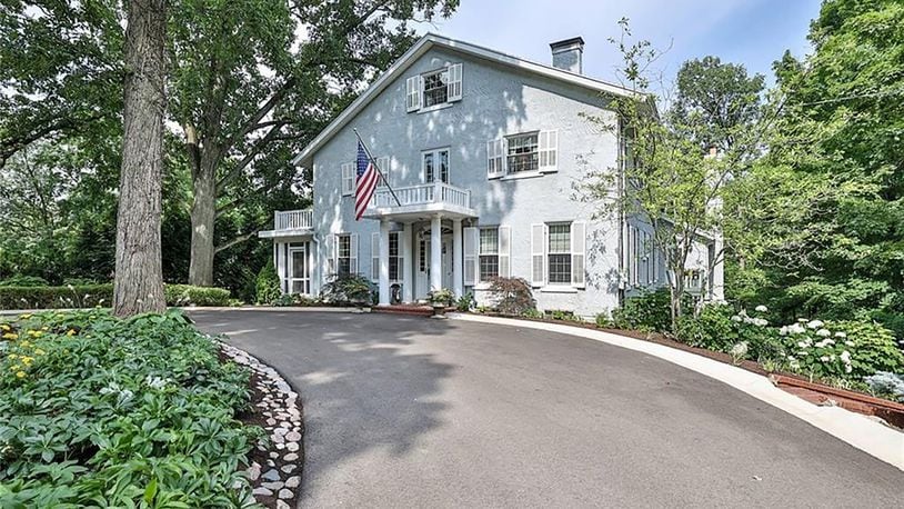 The circular driveway connects the road to the front of the home, which has a covered portico and brick porch.