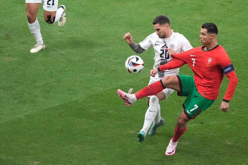 Portugal's Cristiano Ronaldo, right, controls the ball by Slovenia's Petar Stojanovic during a round of sixteen match between Portugal and Slovenia at the Euro 2024 soccer tournament in Frankfurt, Germany, Monday, July 1, 2024. (AP Photo/{Michael Probst)