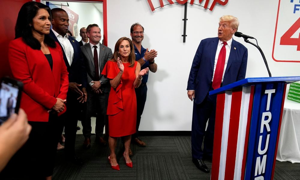 Former Rep. Tulsi Gabbard of Hawaii, left, and Rep. Lisa McClain, R-Mich., third from right, look on as Republican presidential nominee former President Donald Trump speaks during a stop at a campaign office, Monday, Aug. 26, 2024, in Roseville, Mich. (AP Photo/Carolyn Kaster)