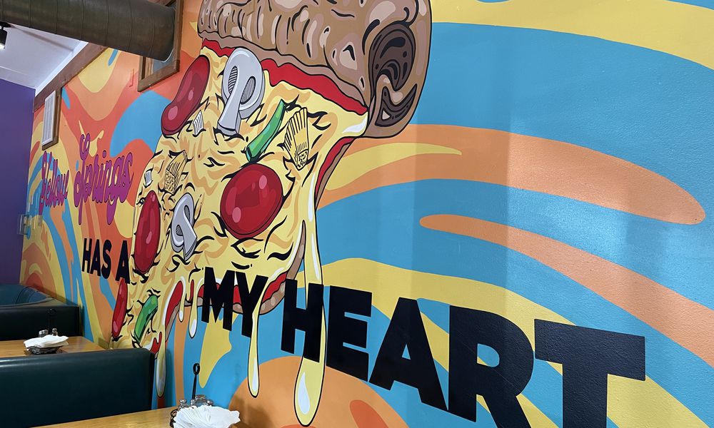 Dayton-area artist Chloé Chicarelli has put her love for Yellow Springs and Ha Ha Pizza on display through a new mural inside the pizza shop. NATALIE JONES/STAFF