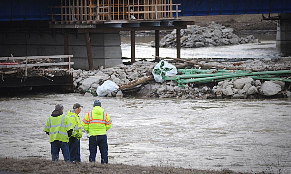 Workers look over debris in the Great Miami River near the Keowee Street Bridge a day after a large water main break interrupted drinking water service to much of Montgomery County on Feb 13, 2019. MARSHALL GORBY / STAFF