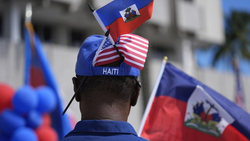 A man wears American and Haitian flags in his hat, as members of South Florida's Haitian-American community listen to speakers during a rally to condemn hate speech and misinformation about Haitian immigrants, Sunday, Sept. 22, 2024, in North Miami, Fla. (AP Photo/Rebecca Blackwell)