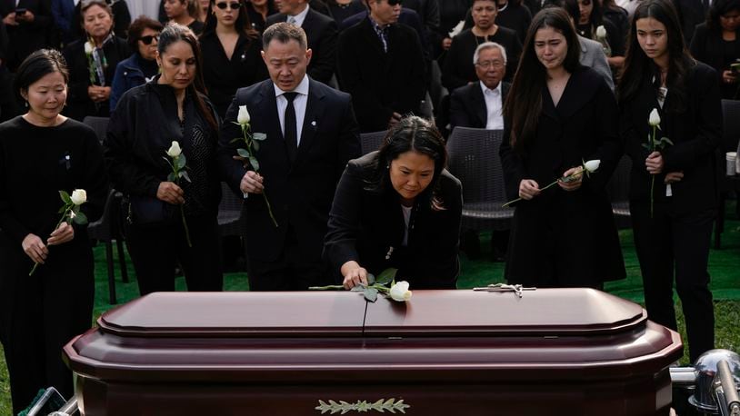 Keiko Fujimori places a flower over the coffin of her father, former President Alberto Fujimori, in Lima, Peru, Saturday, Sept. 14, 2024. (AP Photo/Guadalupe Pardo)