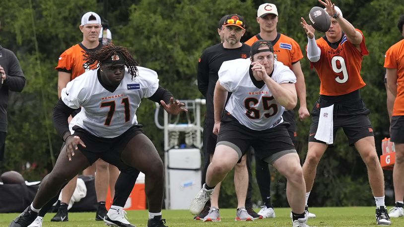 Cincinnati Bengals tackle Amarius Mims (71) and guard Alex Cappa (65) run a play as quarterback Joe Burrow (9) takes a snap from the center during the NFL football team's practice on Tuesday, May 14, 2024, in Cincinnati. (AP Photo/Carolyn Kaster)