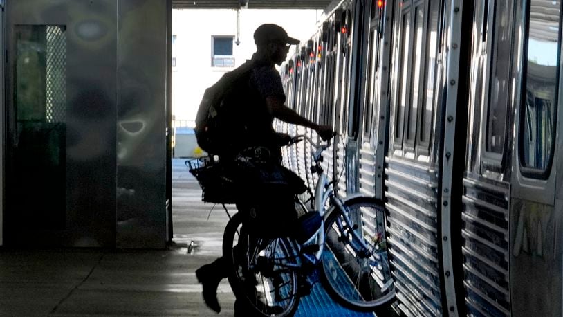 A cyclist enters a Chicago Transit Authority Blue Line train at the Forest Park., Ill., station headed East to Chicago, Tuesday, Sept. 3, 2024, in Forest Park. (AP Photo/Charles Rex Arbogast)