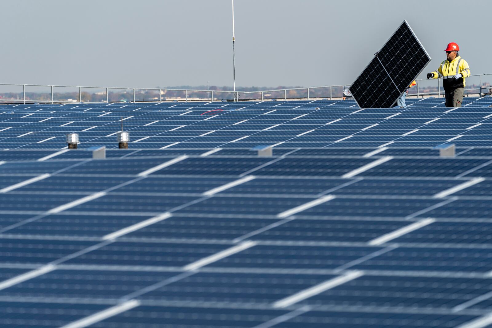 FILE - Electricians with IBEW Local 3 install solar panels on top of the Terminal B garage at LaGuardia Airport, Nov. 9, 2021, in the Queens borough of New York. (AP Photo/Mary Altaffer, File)