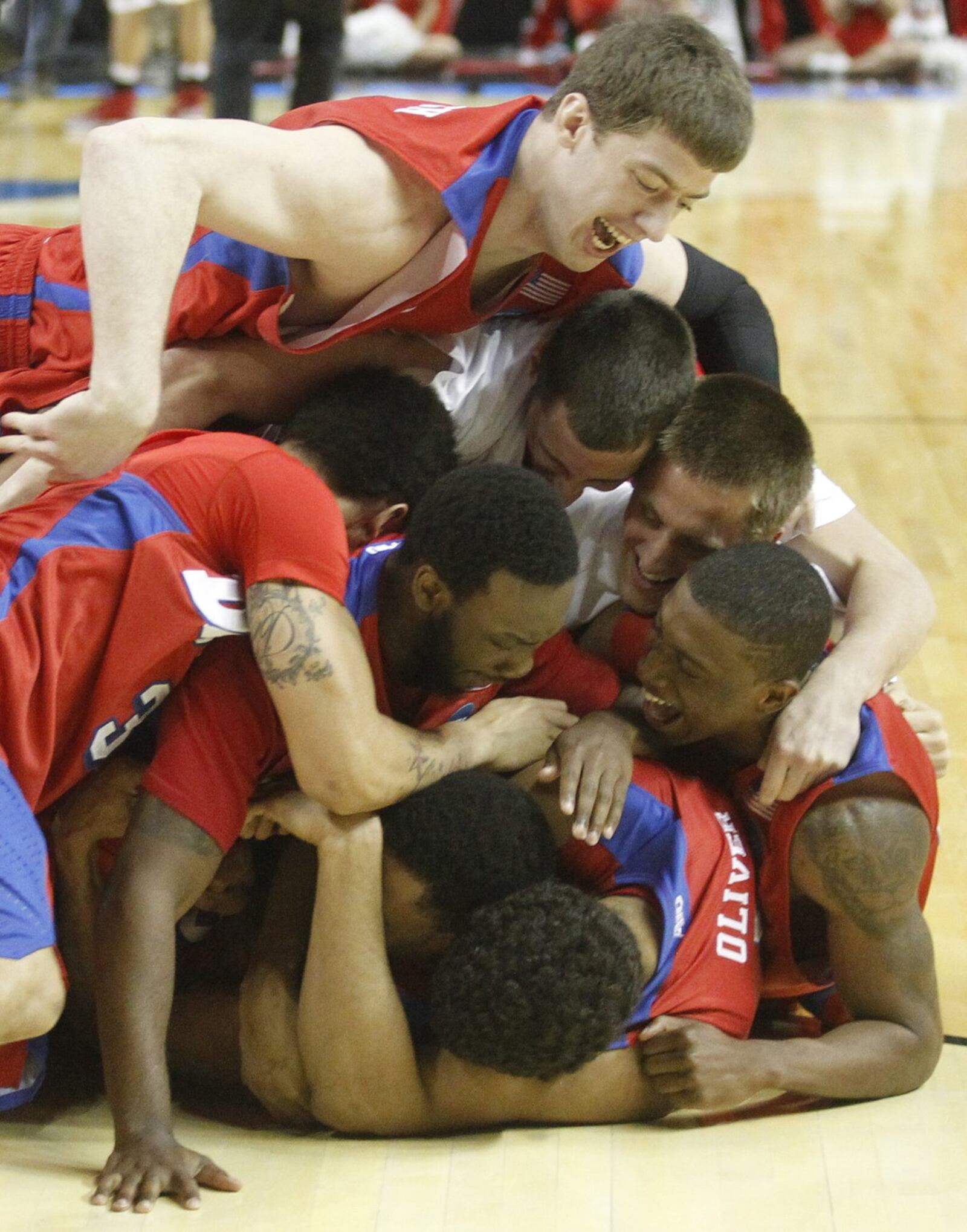 Matt Kavanaugh, top, and the Flyers jump on Vee Sanford after his game-winning shot against Ohio State in the second round of the NCAA tournament on March 20, 2014, in Buffalo, N.Y. David Jablonski/Staff