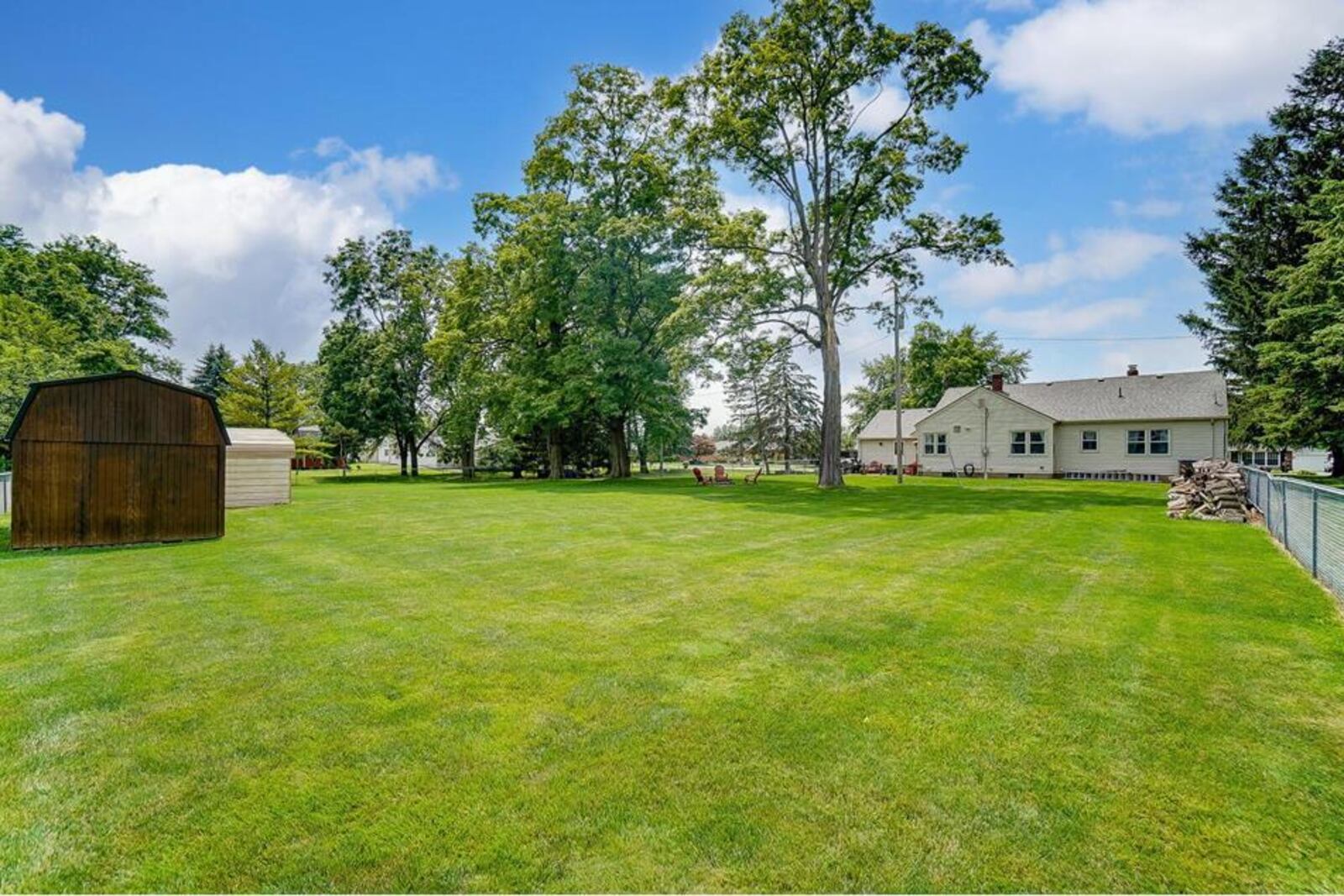 The rear of the home features a concrete patio, shed and covered car port and chain link fence.