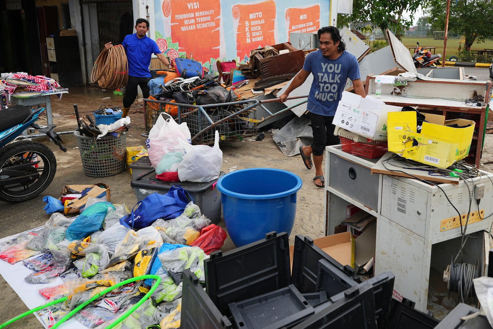 Men remove items from a school affected by a flood in Tumpat, on the outskirts of Kota Bahru, Malaysia, Tuesday, Dec. 3, 2024. (AP Photo/Vincent Thian)