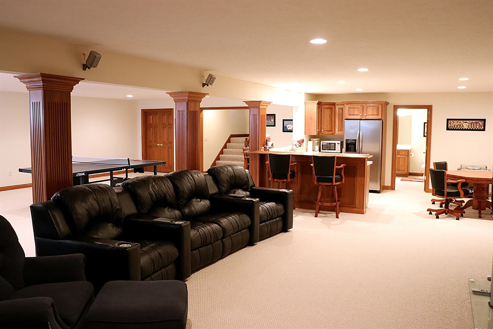 An open stairwell leads into the finished basement, which is divided into a family room and recreation room. Fluted wood support pillars divide the space and complement the wet bar and kitchenette cabinetry. CONTRIBUTED PHOTO BY KATHY TYLER