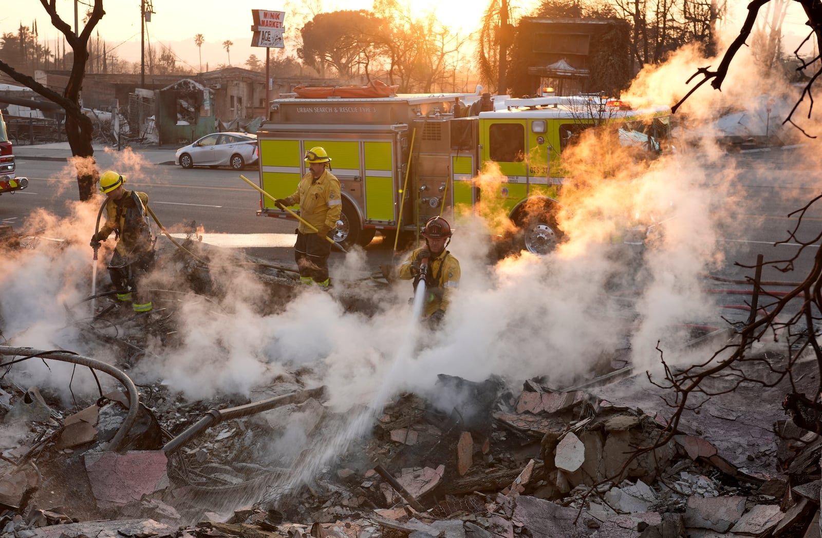 Firefighters extinguish burning embers at the site of a structure on Lake Avenue destroyed by the Eaton Fire, Friday, Jan. 10, 2025, in Altadena, Calif. (AP Photo/Chris Pizzello)