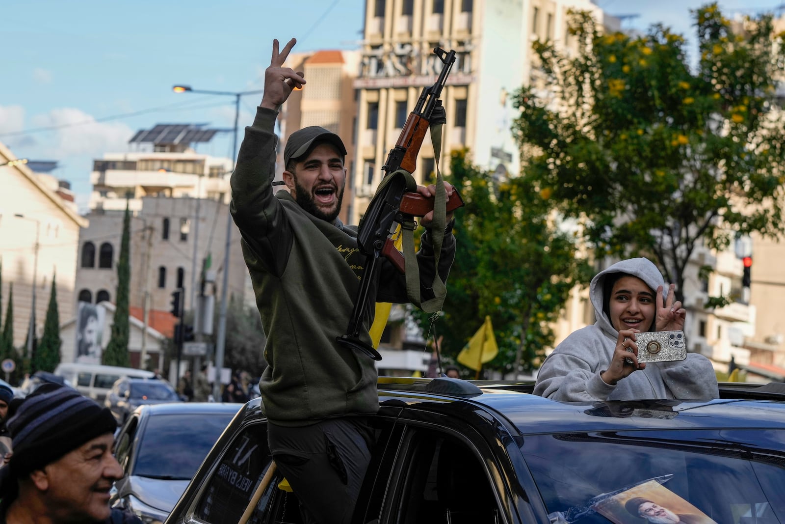 A Hezbollah supporter shoots in the air in celebration as displaced residents return to Dahiyeh, in Beirut, Lebanon, following a ceasefire between Israel and Hezbollah that went into effect on Wednesday, Nov. 27, 2024. (AP Photo/Bilal Hussein)