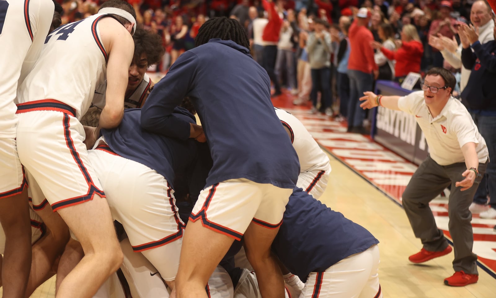 Dayton fan Colin Connor, right, watches the team celebrate after the last-second shot by Amaël L'Etang in overtime against Loyola Chicago on Saturday, Jan. 18, 2025, at UD Arena. David Jablonski/Staff