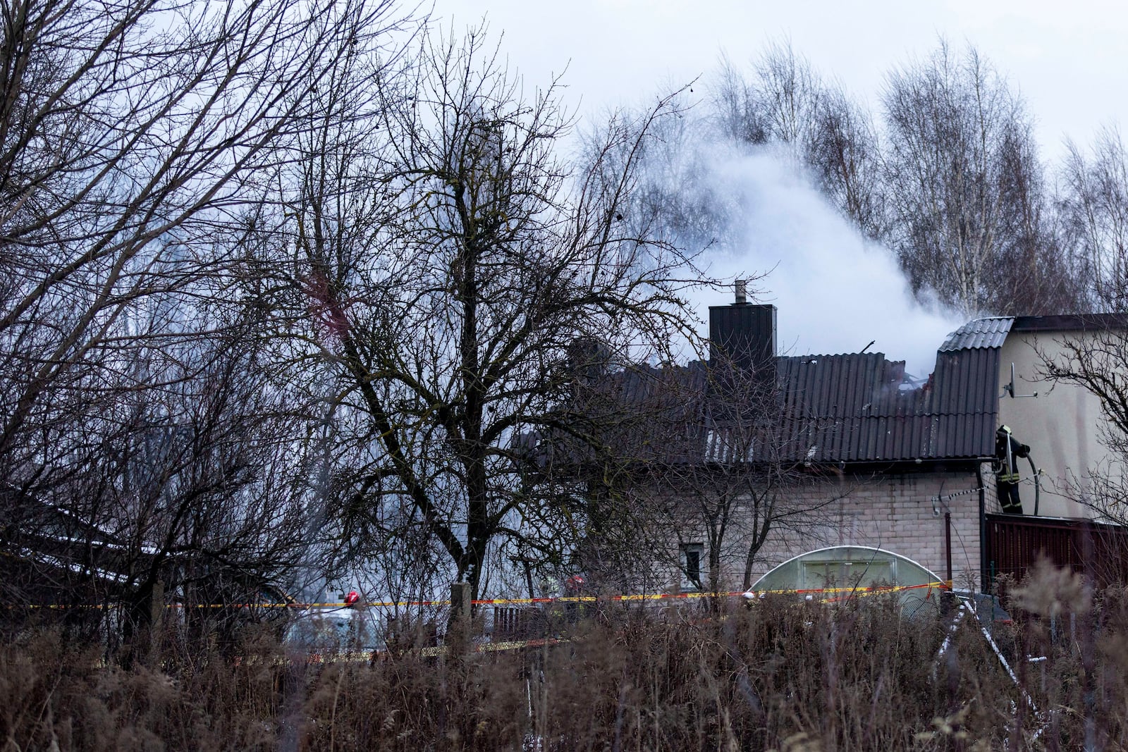 A smoke rises from the place where a DHL cargo plane crashed into a house near the Lithuanian capital Vilnius, Lithuania, Lithuania, Monday, Nov. 25, 2024. (AP Photo/Mindaugas Kulbis)