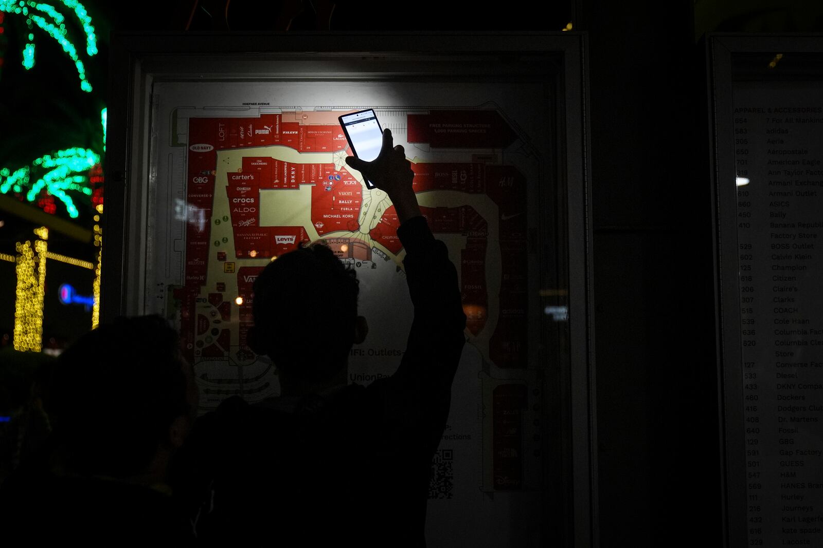 An early Black Friday shopper uses a smartphone flashlight to locate a store at Citadel Outlets in Commerce, Calif., Thursday, Nov. 28, 2024. (AP Photo/Jae C. Hong)