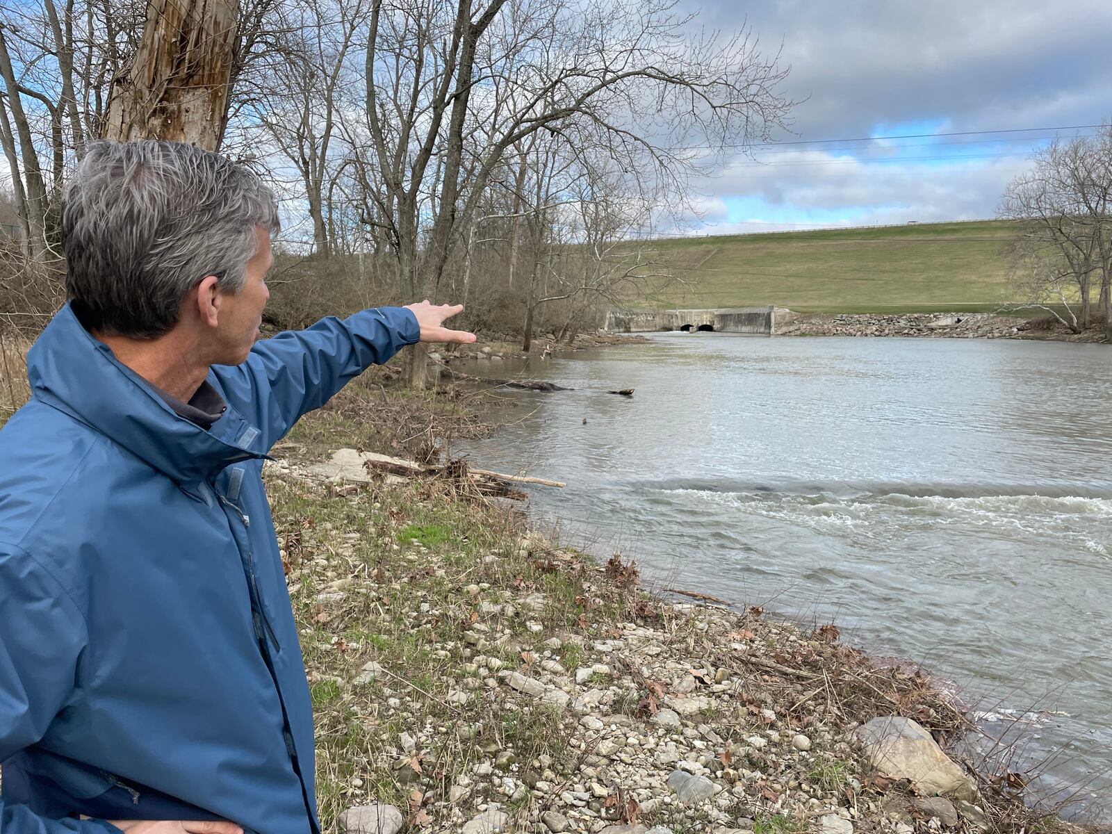 Mike Ekberg, manager of water data and analysis for the Miami Conservancy District, points to the Englewood Dam while standing on the banks of the Stillwater River in Englewood on a recent morning. Ekberg, who is also a hydrologist, said the river is in great health. ISMAIL TURAY JR. / STAFF