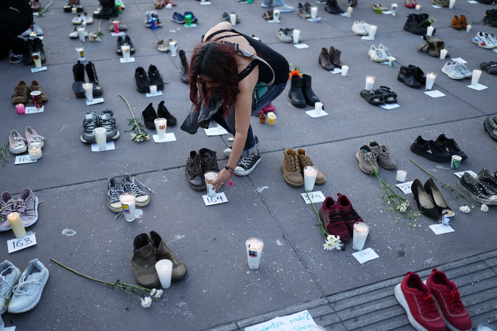 A demonstrator places shoes at the Zocalo, Mexico City's main square, Saturday, March 15, 2025, as part of a vigil for victims whose skeletal remains were discovered at a ranch in Jalisco state. (AP Photo/Eduardo Verdugo)