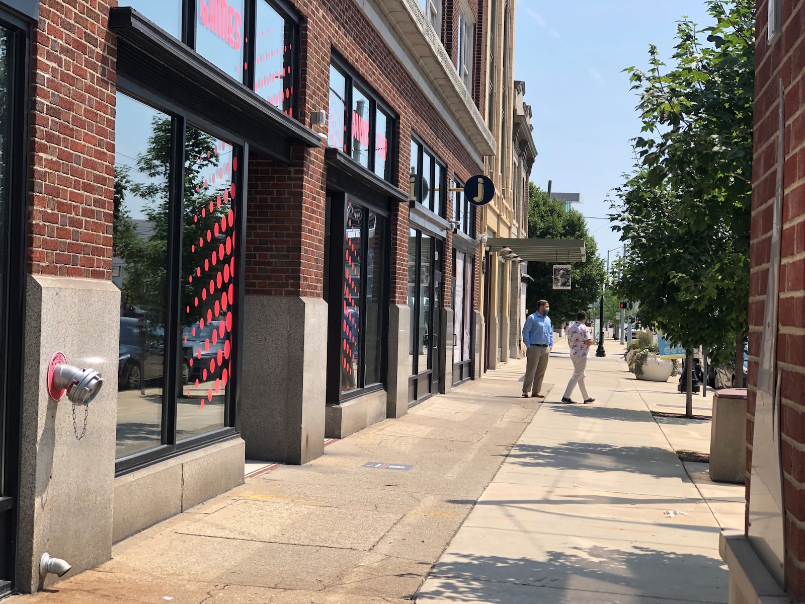 Pedestrians walk past the colorful windows of the new Two Social space on East Third Street in the Fire Blocks District. The business will have bar games and axe throwing. CORNELIUS FROLIK / STAFF