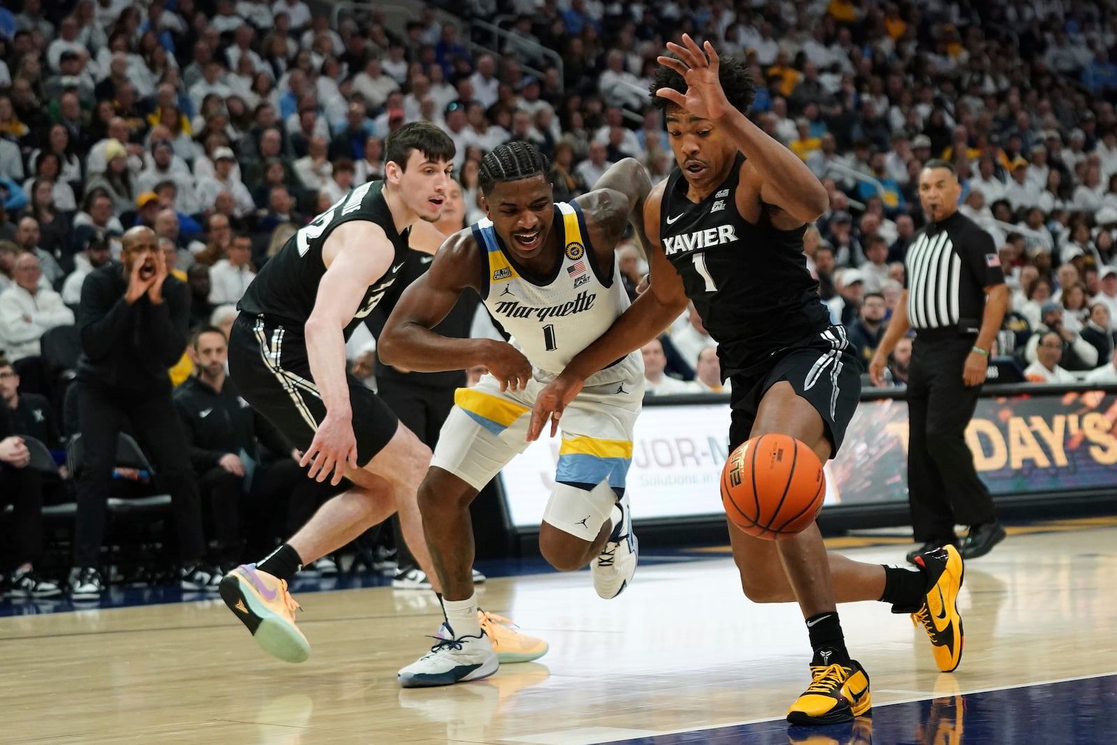 Marquette's Kam Jones, center, loses control of the ball against Xavier's Marcus Foster, right, during the first half of an NCAA college basketball game Saturday, Jan. 18, 2025, in Milwaukee. (AP Photo/Aaron Gash)