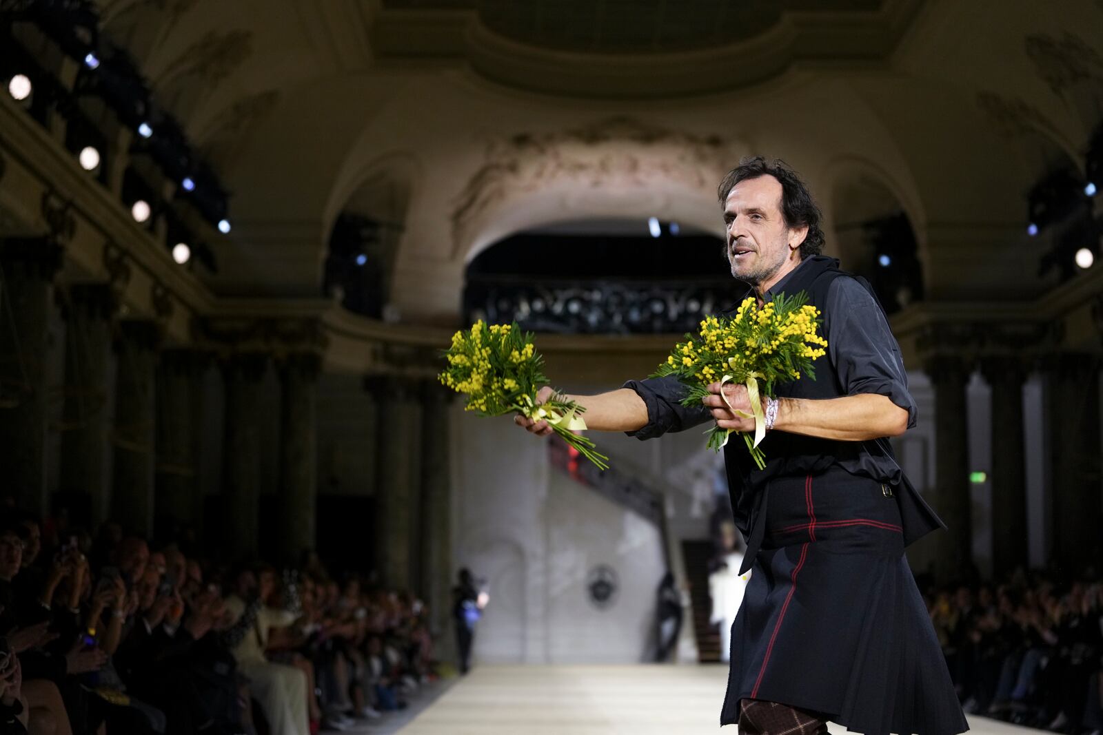 Designer Andreas Kronthaler hands out flowers after the Vivienne Westwood Fall/Winter 2025-2026 Womenswear collection presented in Paris, Saturday, March 8, 2025. (Photo by Scott A Garfitt/Invision/AP)