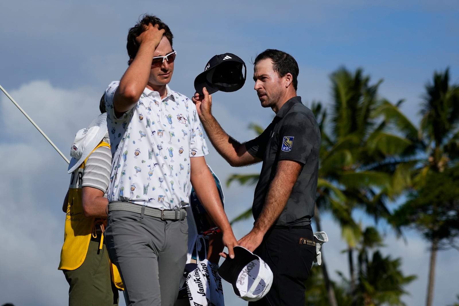 Nico Echavarria, left, of Columbia, walks away as Nick Taylor, of Canada, celebrates after winning their playoff in the final round of the Sony Open golf event, Sunday, Jan. 12, 2025, at Waialae Country Club in Honolulu. (AP Photo/Matt York)