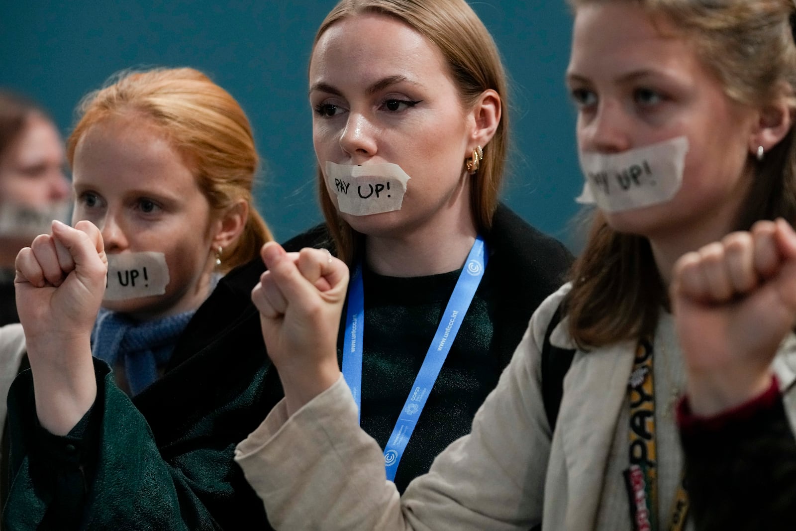 Attendees have "pay up" taped on their mouth during the People's Plenary at the COP29 U.N. Climate Summit, Thursday, Nov. 21, 2024, in Baku, Azerbaijan. (AP Photo/Rafiq Maqbool)