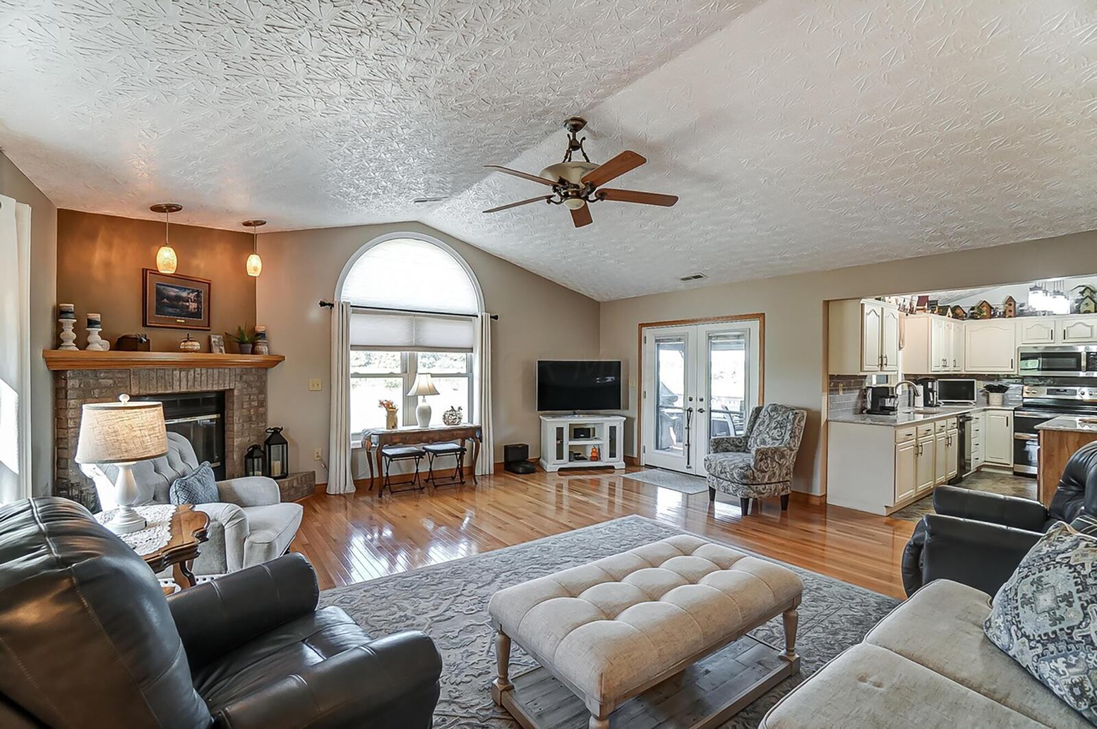 the great room has vaulted ceilings, a brick gas fireplace and hardwood flooring. It walks out to the covered rear deck.