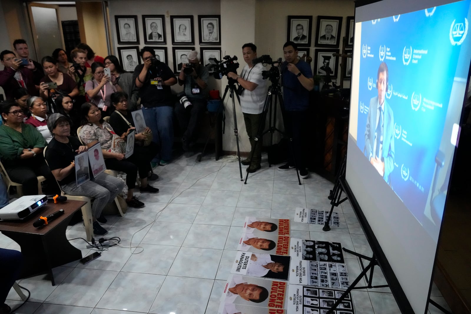 Relatives of victims of the drug war of former President Rodrigo Duterte and activists watch a broadcast of his first appearance at the International Criminal Court (ICC) as they gather in Quezon city, Philippines on Friday, March 14, 2025. (AP Photo/Aaron Favila)