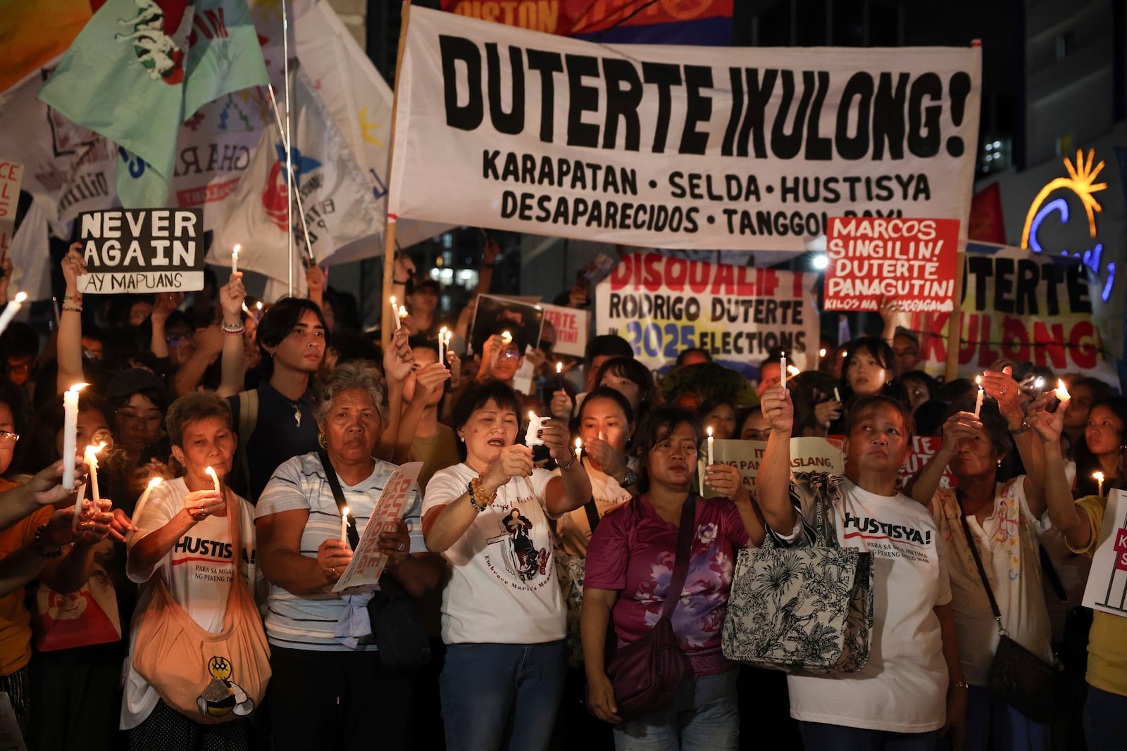 Relatives of victims of drug war and extrajudicial killings and activists hold signs and light candles during a protest against former Philippine President Rodrigo Duterte following his arrest in Quezon City, Philippines, Tuesday, March 11, 2025. (AP Photo/Basilio Sepe)