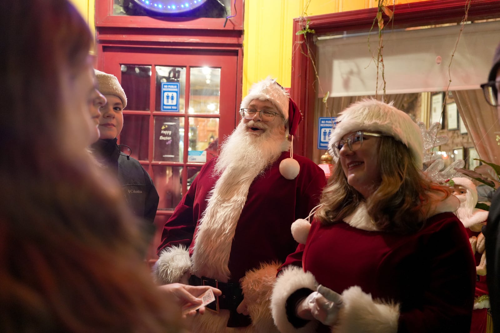 Dressed as Santa and Mrs., Claus, Gordon Crowell Jr. and Ellen Crowell greet people outside a restaurant in in Bethlehem, Pa., on Friday, Nov. 29, 2024. (AP Photo/Luis Andres Henao)