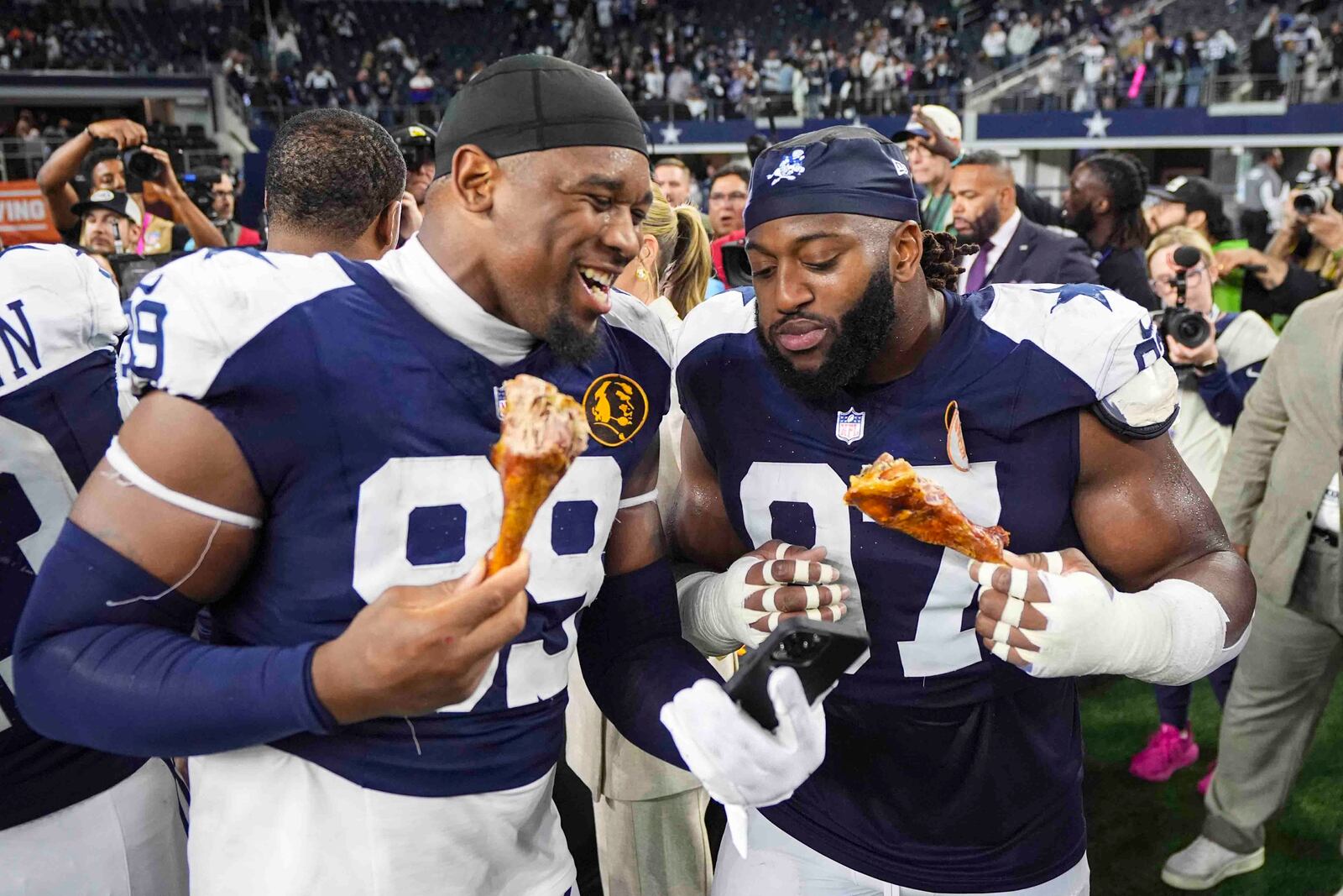 Dallas Cowboys defensive end Chauncey Golston (99) and defensive tackle Osa Odighizuwa (97) eat a turkey leg following an NFL football game against the New York Giants in Arlington, Texas, Thursday, Nov. 28, 2024. (AP Photo/Tony Gutierrez)