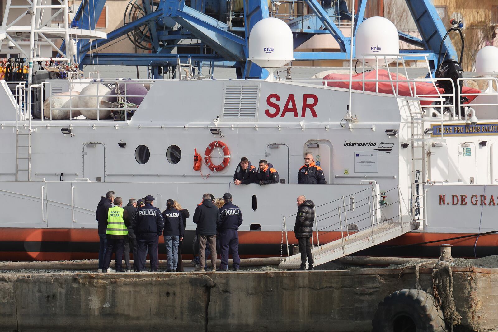 Crew members of an Italian Coast Guard vessel stand at a promenade, ahead of a transfer operation of migrants from the asylum processing centers in Albania back to Italy, in Shengjin, northwestern Albania, Saturday, Feb. 1, 2025. (AP Photo/Vlasov Sulaj)