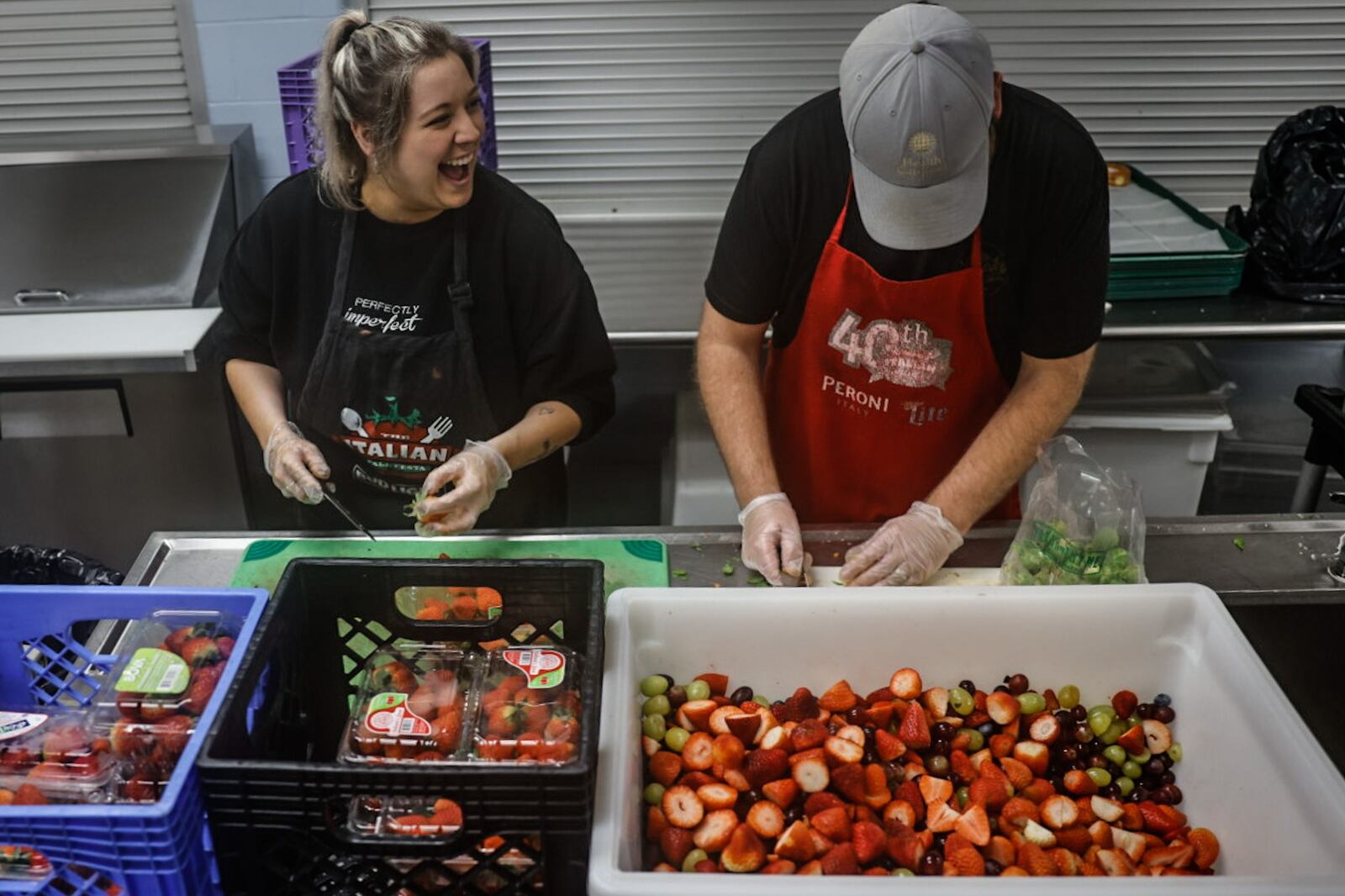 House of Bread volunteers from left, Alli Hachey and Luke Bohardt, create a fruit medley at the House of Bread on Orth Avenue in Dayton. JIM NOELKER/STAFF