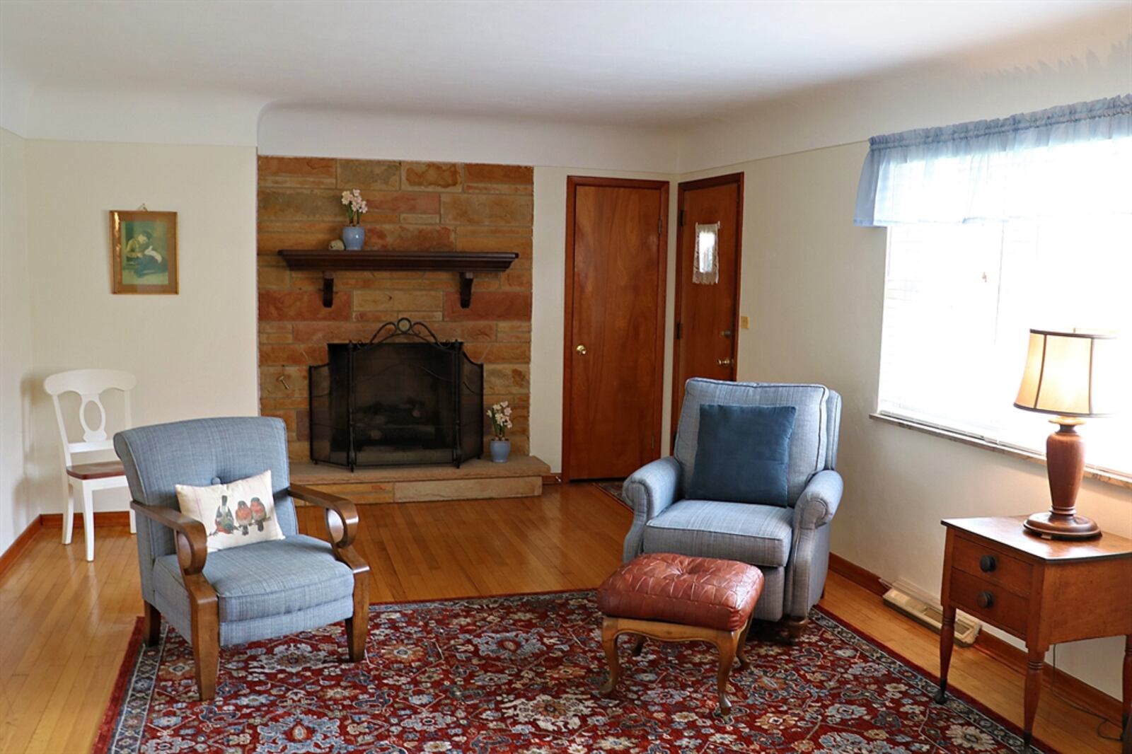 A stone fireplace with a raised stone hearth and wood-beam mantel highlights the living room.