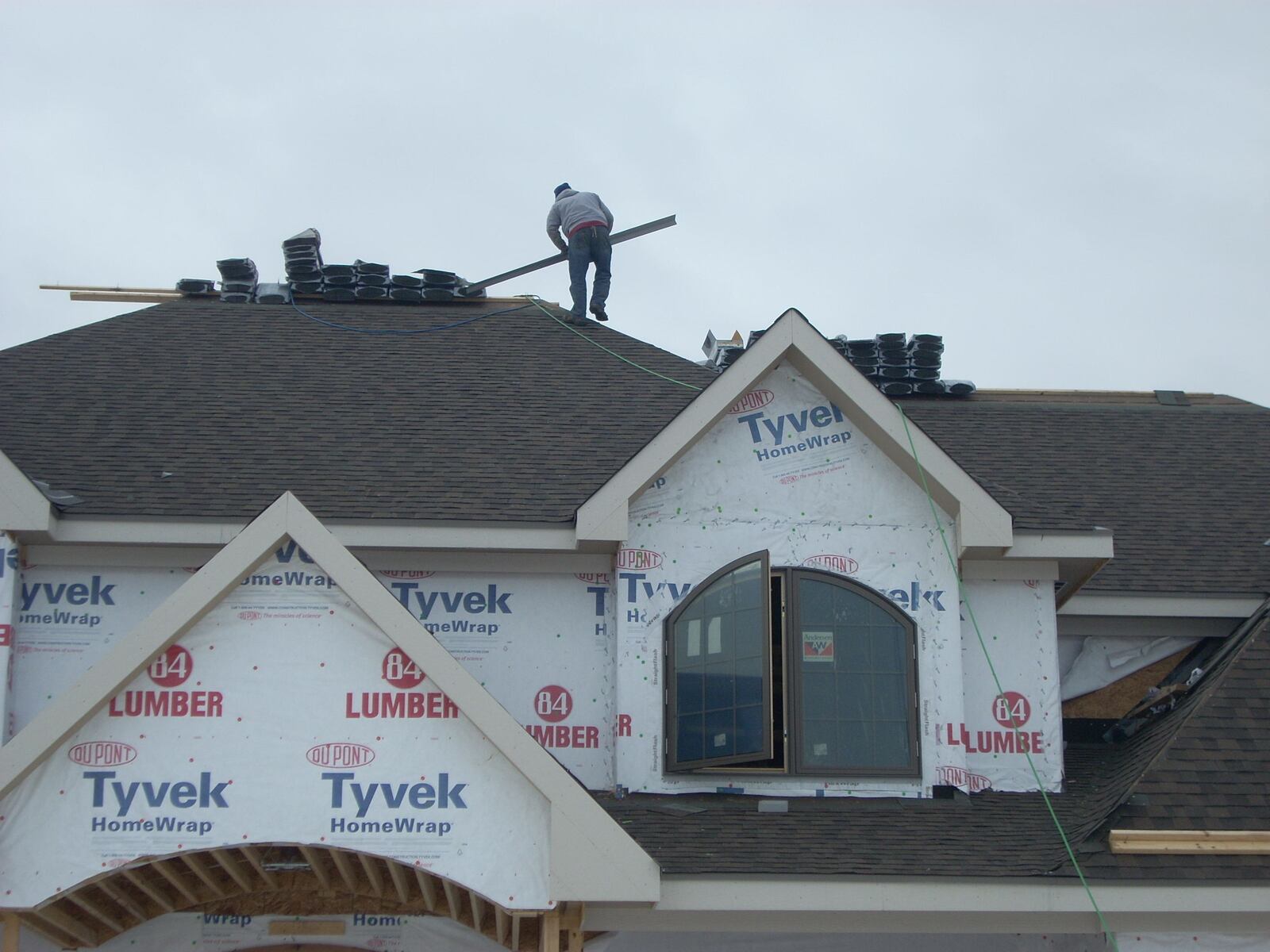 Roofing contractors work on a new home in Pine View Estates in Sugarcreek Twp.