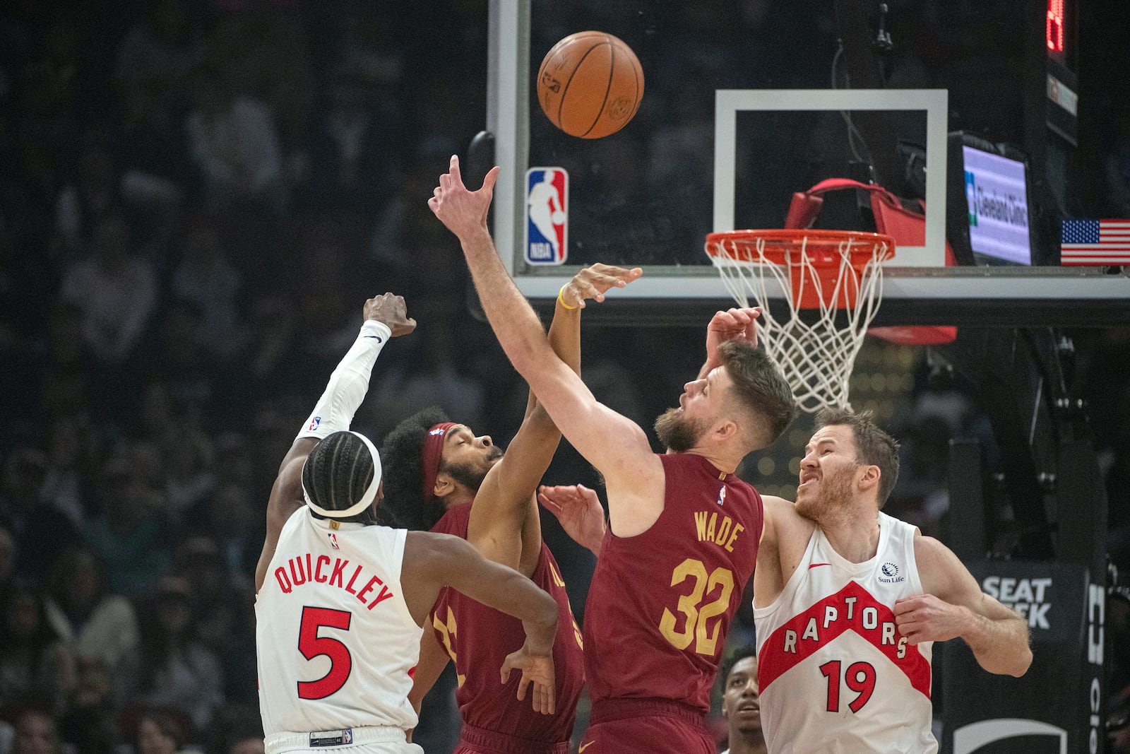 Toronto Raptors' Immanuel Quickley (5), Cleveland Cavaliers' Jarrett Allen, center left, Cavaliers' Dean Wade (32) and Raptors' Jakob Poeltl (19) vie for a rebound during the first half of an NBA basketball game in Cleveland, Thursday, Jan. 9, 2025. (AP Photo/Phil Long)