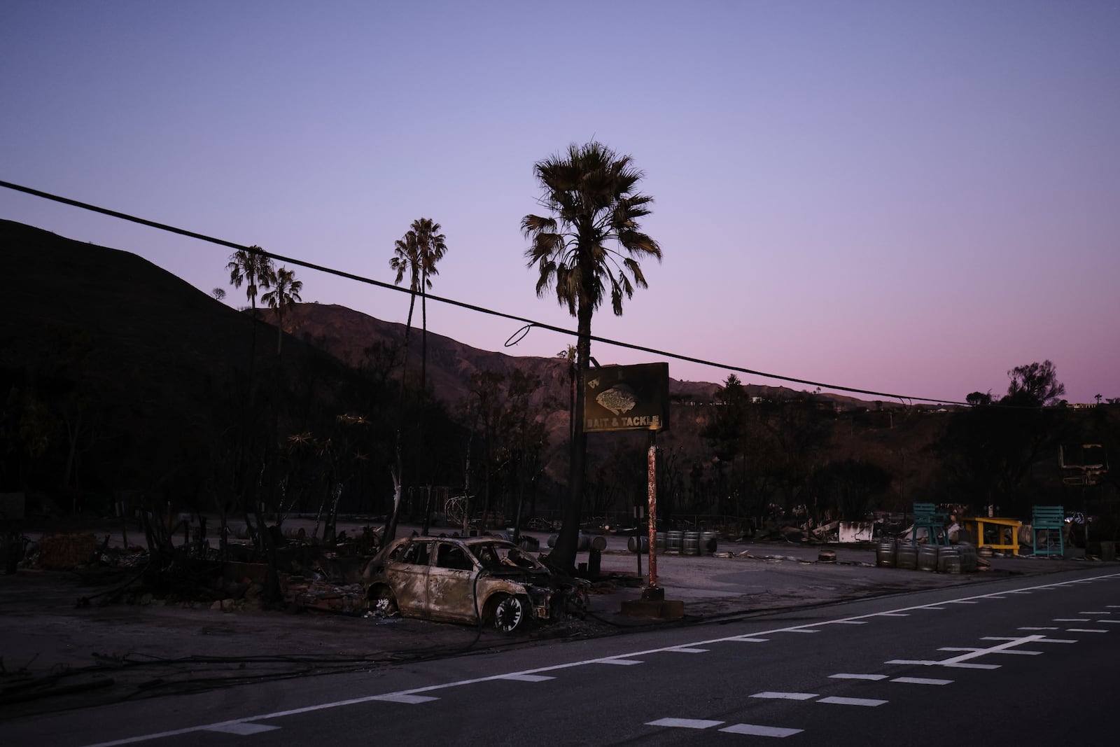 A burnt car destroyed by the Palisades Fire is seen, Tuesday, Jan. 14, 2025, in Malibu, Calif. (AP Photo/Ethan Swope)