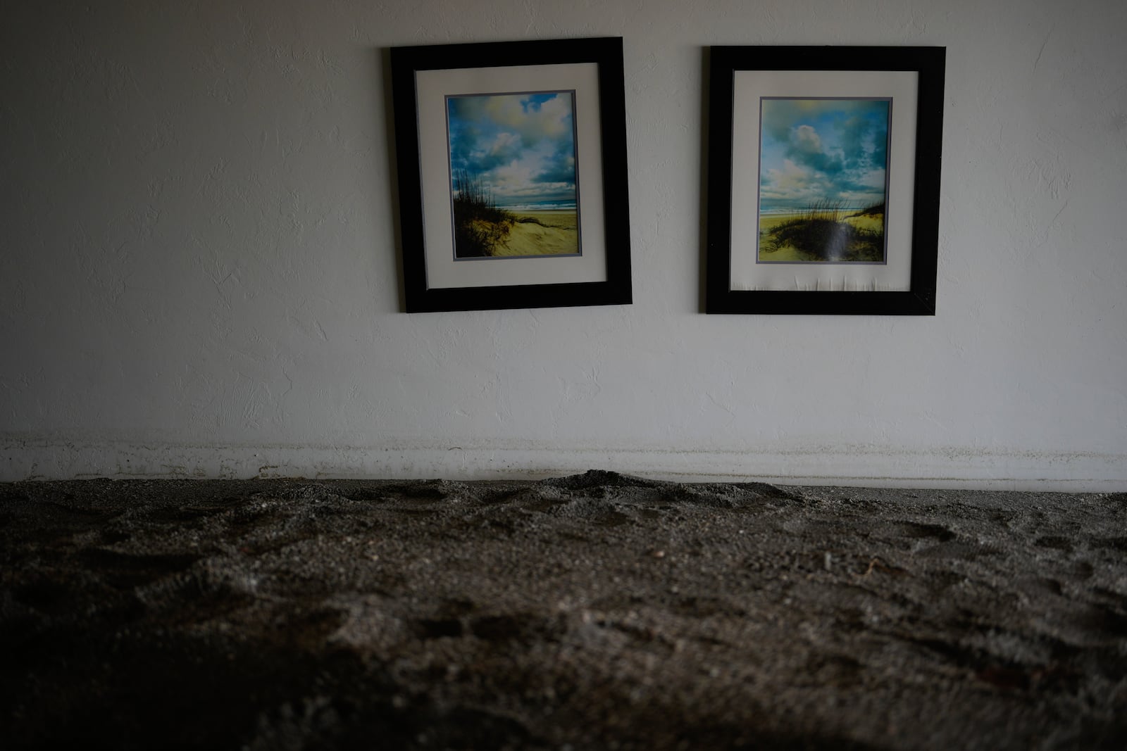 Paintings hang above several feet of sand filling a condo following the passage of Hurricane Milton, at YCA Vacation Rentals in Venice, Fla., Friday, Oct. 11, 2024. (AP Photo/Rebecca Blackwell)