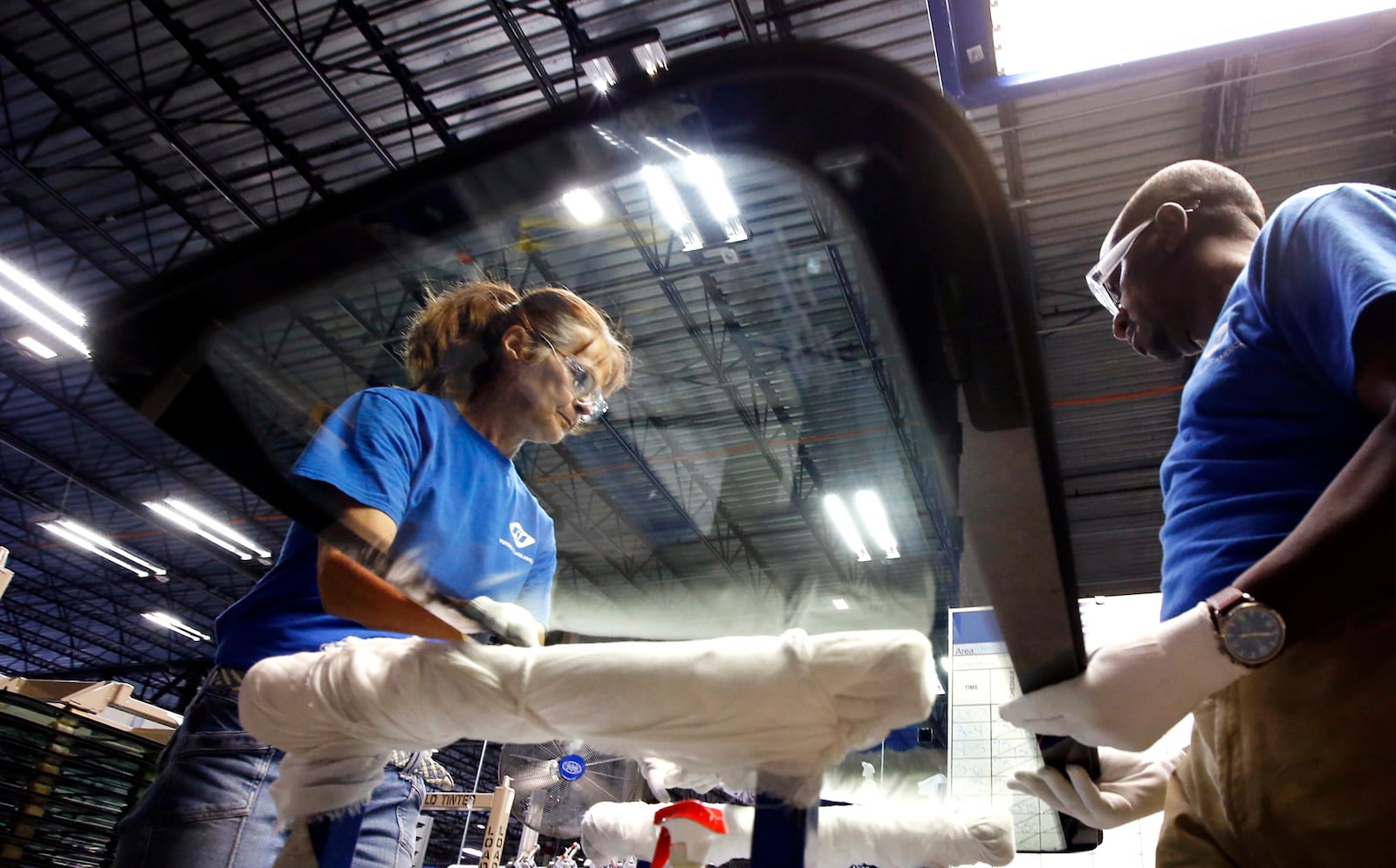 Workers at Fuyao Glass America finish an automobile windshield in the Moraine plant.  Fuyao currently employs 2,300 workers and expects to need 700 more in 2019.   TY GREENLEES / STAFF