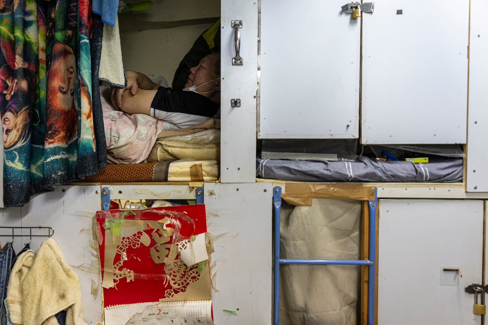 A resident rests in his bed space in Sham Shui Po district of Hong Kong, on Feb. 6, 2025. (AP Photo/Chan Long Hei)