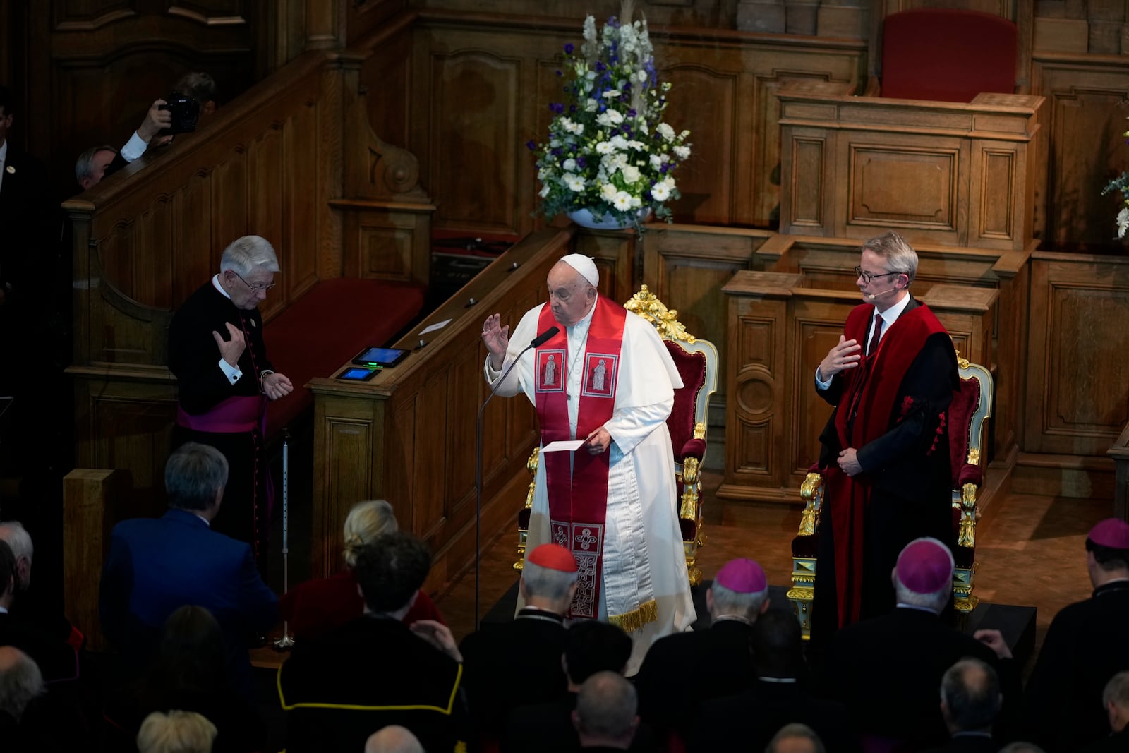 Pope Francis, left, flanked by Rector Luc Sels, delivers his blessing during his meeting with the professors in the Promotiezaal of the Catholic University of Leuven, Belgium, Friday, Sept. 27, 2024. (AP Photo/Andrew Medichini)