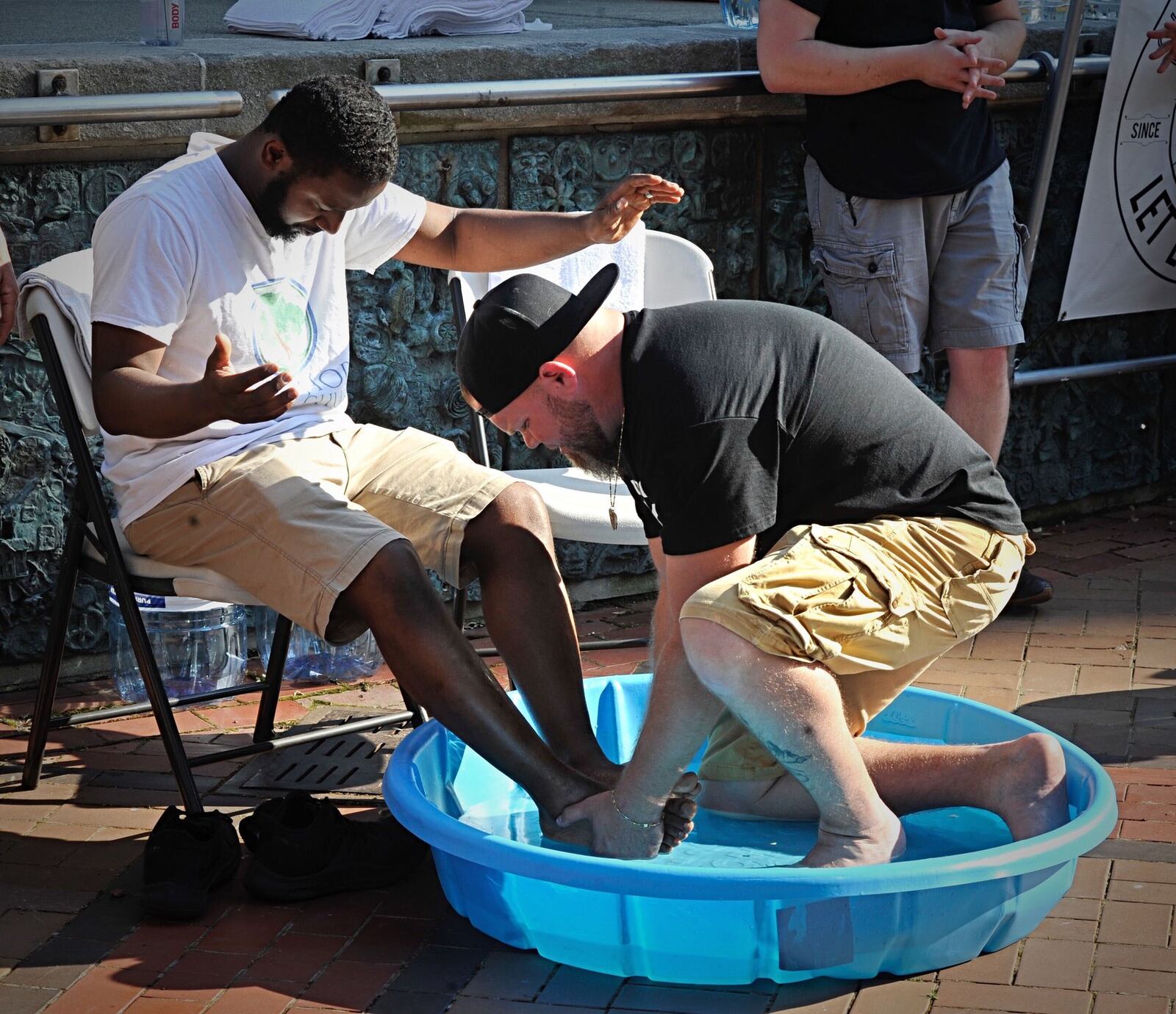 Pastor Israel Baxter of New Hope Life Church and Pastor Joel Burton of Simple Street Ministry, right, wash each other s feet in front of a small crowd at Courthouse Square to bring ministry to the square. MARSHALL GORBYSTAFF