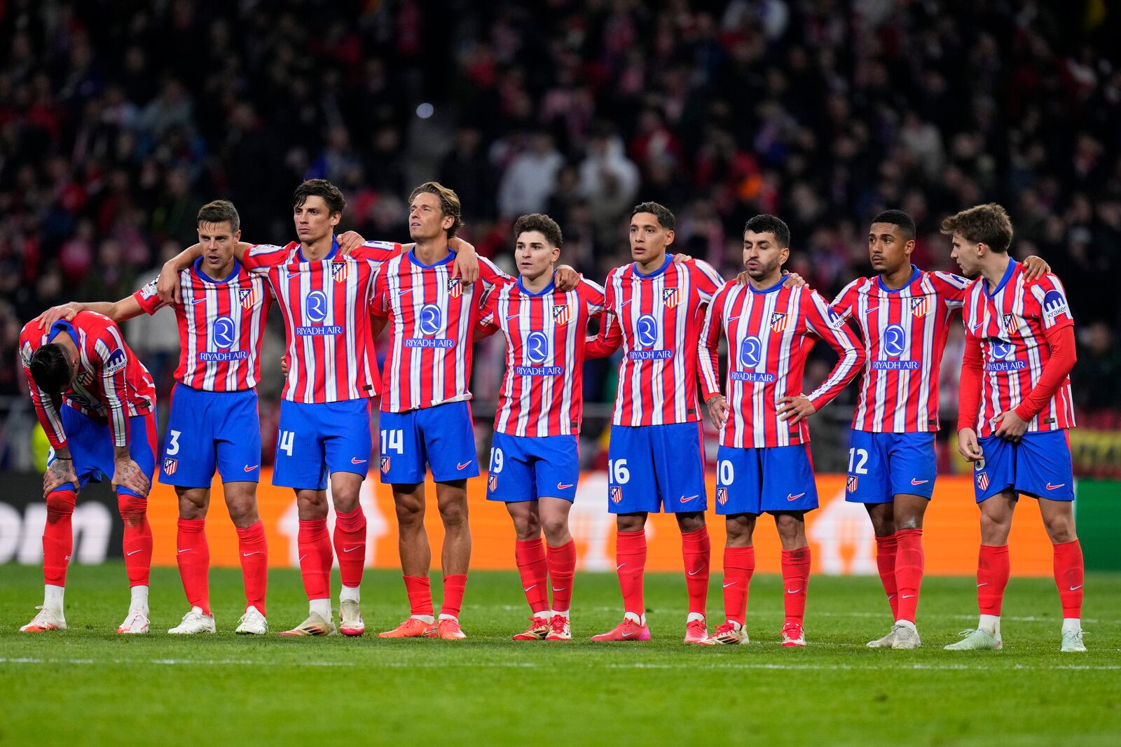 Atletico Madrid players stand together during a penalty shootout at the end of the Champions League round of 16, second leg, soccer match between Atletico Madrid and Real Madrid at the Metropolitano stadium in Madrid, Spain, Wednesday, March 12, 2025. (AP Photo/Manu Fernandez)