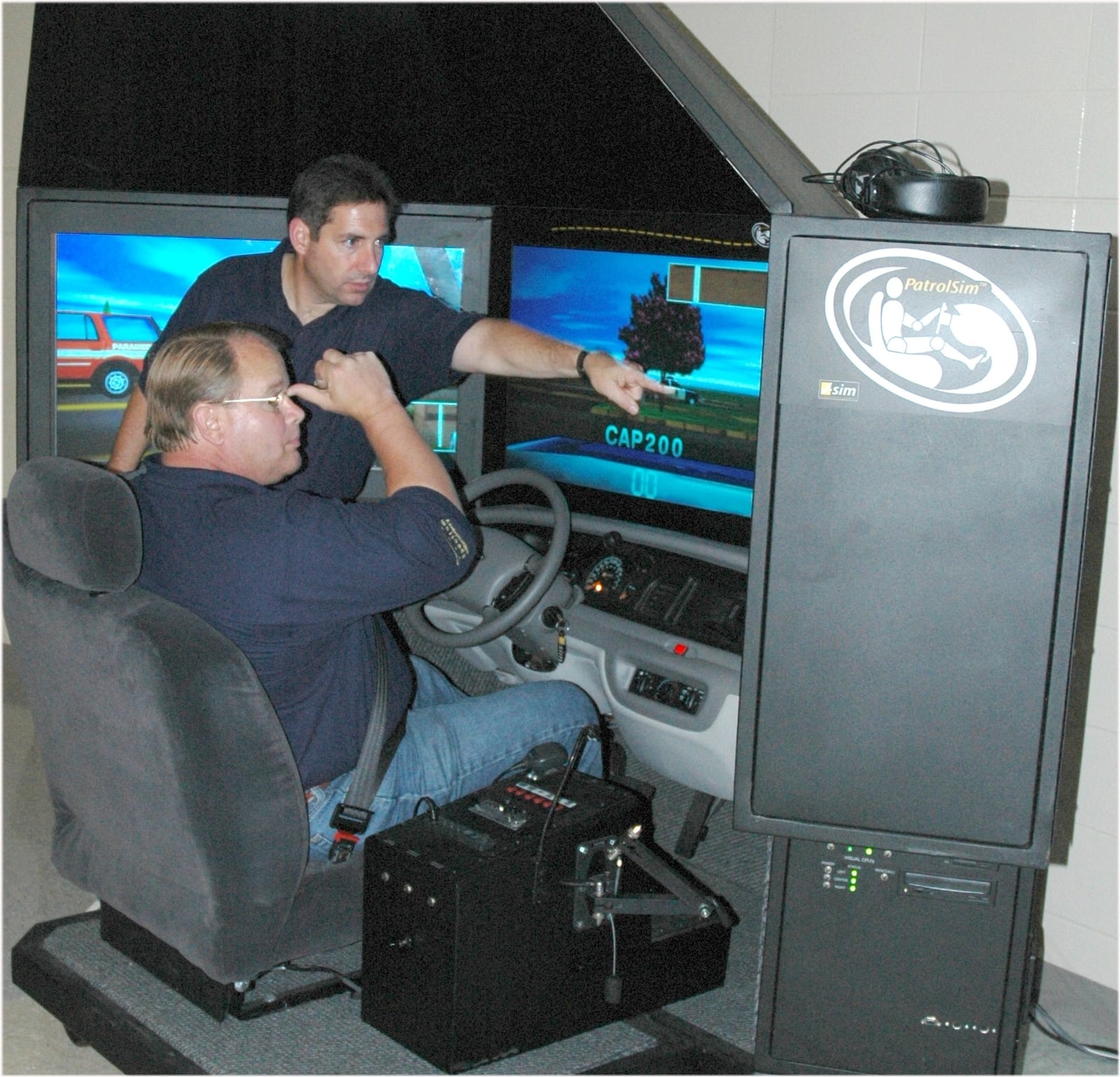 West Carrollton Police Chief Doug Woodard teaches former West Carrollton Mayor Jeff Sanner how to navigate a driving simulation in this undated photo. CONTRIBUTED