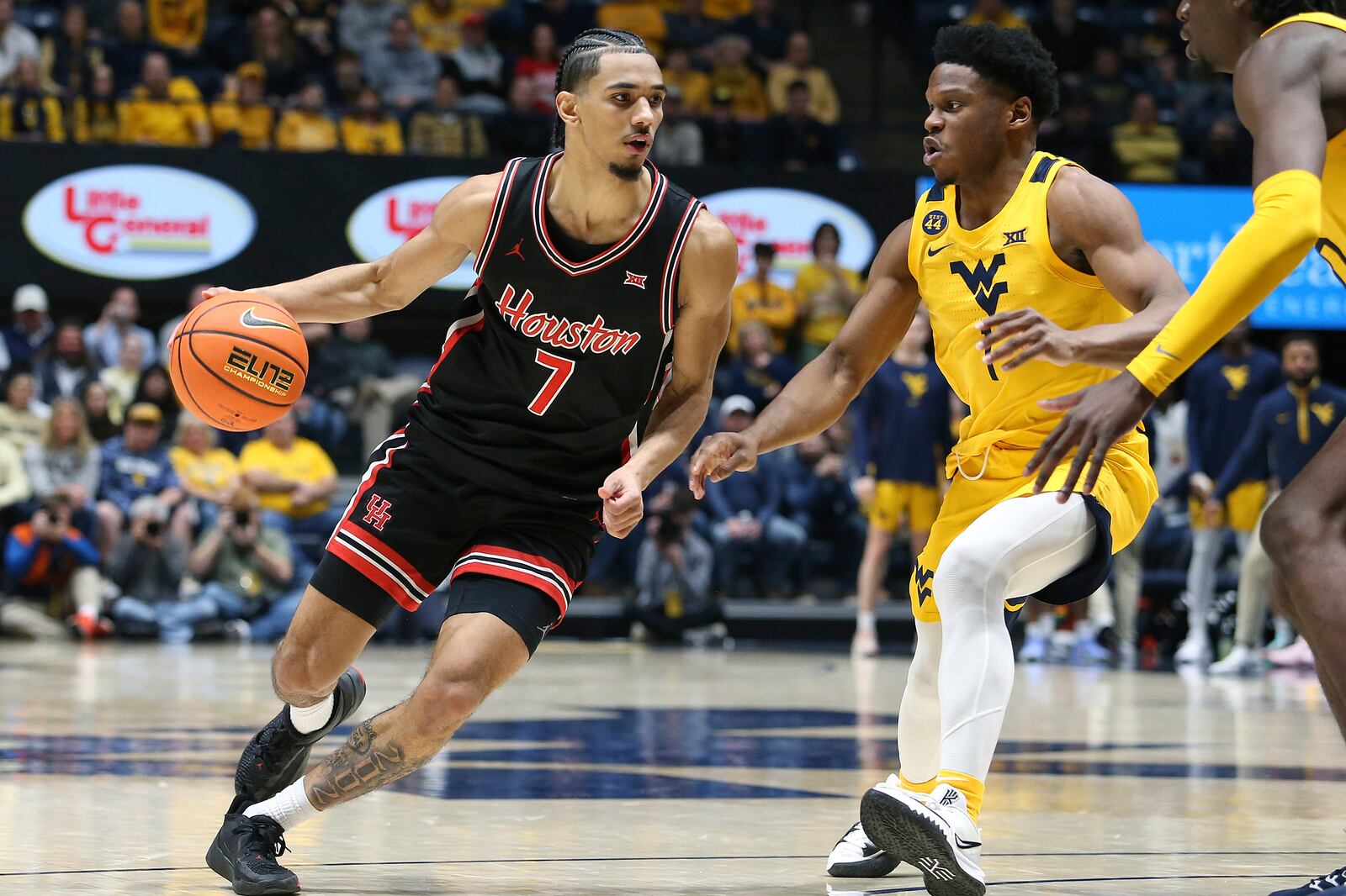 Houston guard Milos Uzan (7) is defended by West Virginia guard Joseph Yesufu (1) during the second half of an NCAA college basketball game Wednesday, Jan. 29, 2025, in Morgantown, W.Va. (AP Photo/Kathleen Batten)