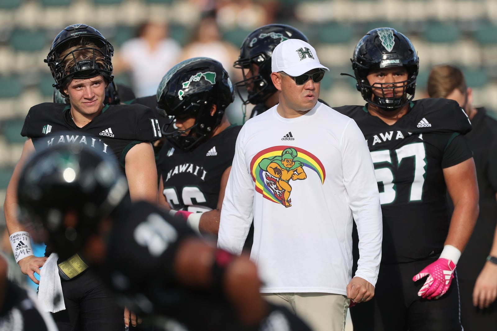 FILE - Hawaii head coach Timmy Chang, front right, wears a shirt showing his team’s Rainbow Warriors mascot before an NCAA college football game against San Diego State, Saturday, Oct. 14, 2023, in Honolulu. (AP Photo/Marco Garcia, File)