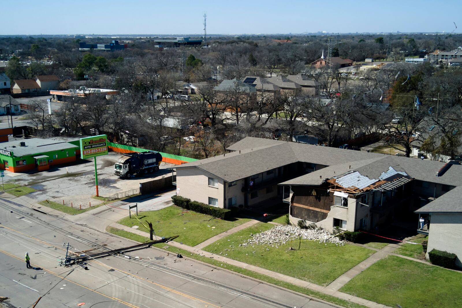 A downed power line rests on the road near an apartment building damaged during early morning storm that hit the Dallas region Tuesday, March 4, 2025, in Irving, Texas. (AP Photo/Julio Cortez)