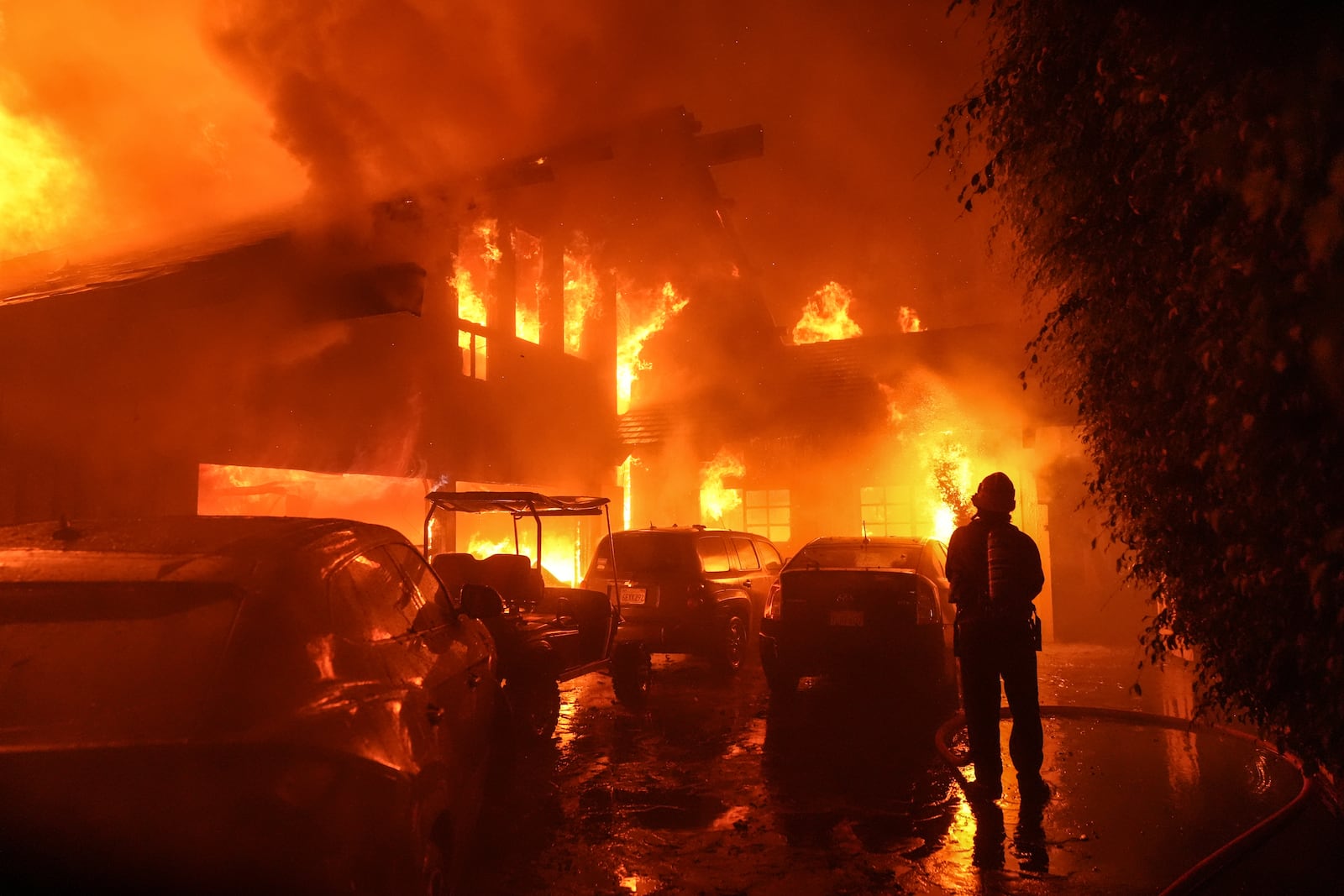 A firefighter sprays water on a home as it burns in the Franklin Fire in Malibu, Calif., Tuesday, Dec. 10, 2024. (AP Photo/Jae C. Hong)