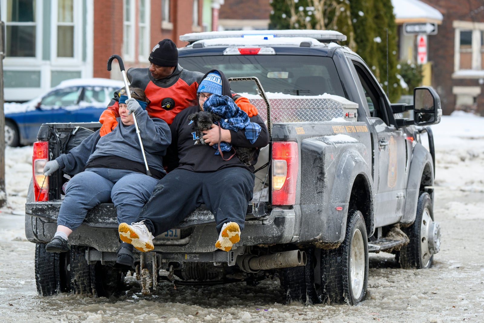 A man, woman and dog are driven to safety in a Detroit Police Department truck after a water main break in Detroit caused massive flooding, triggering evacuations, Monday, Feb. 17, 2025. (Andy Morrison/Detroit News via AP)